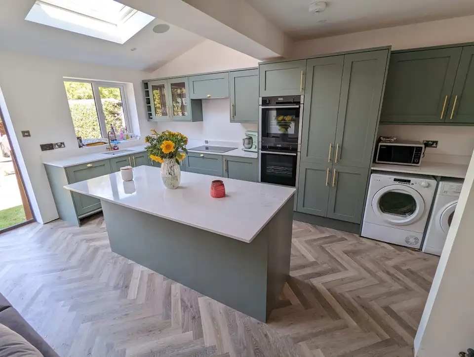 Sage green shaker kitchen with a quartz-topped island and herringbone floor, fitted by S.Wilson Joinery in Sale