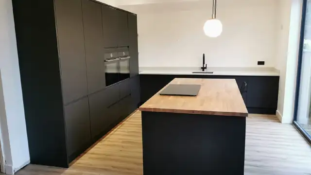 Black handleless kitchen with a solid oak island and hob