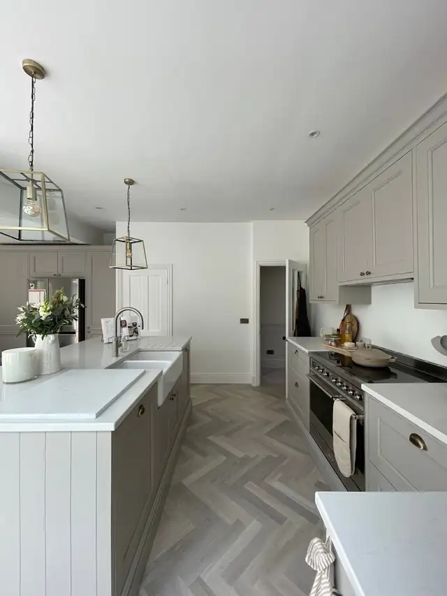 Sage and white shaker kitchen with a Belfast sink and tall units