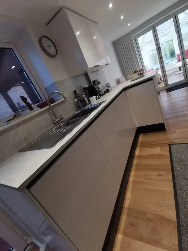Grey handleless units and worktop with a sink under the window