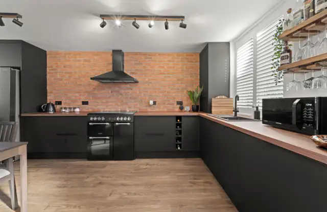 Black kitchen with brick wall and wooden worktops